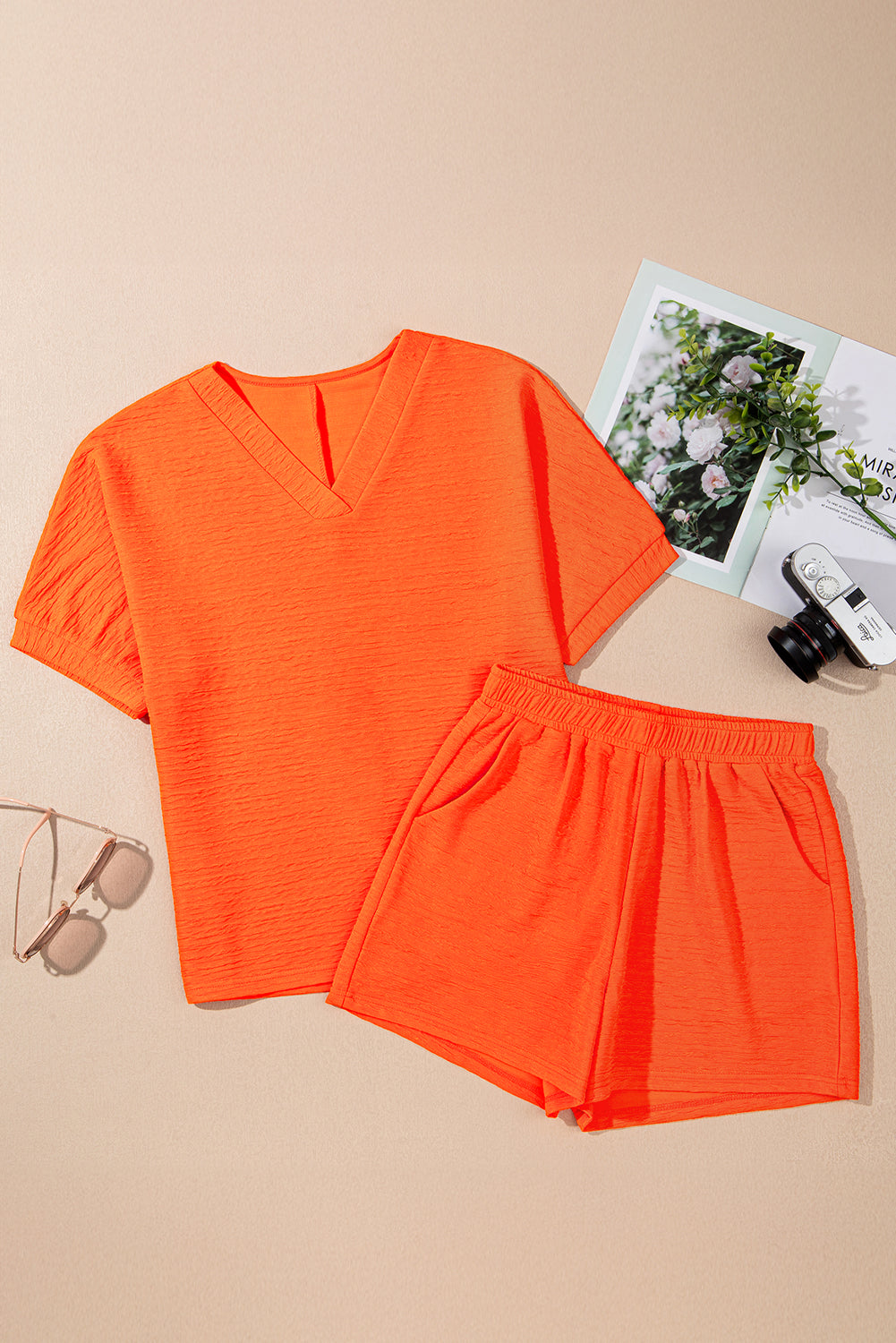 Flat lay of a bright orange textured two-piece shorts set featuring a relaxed fit top and elastic waist shorts.