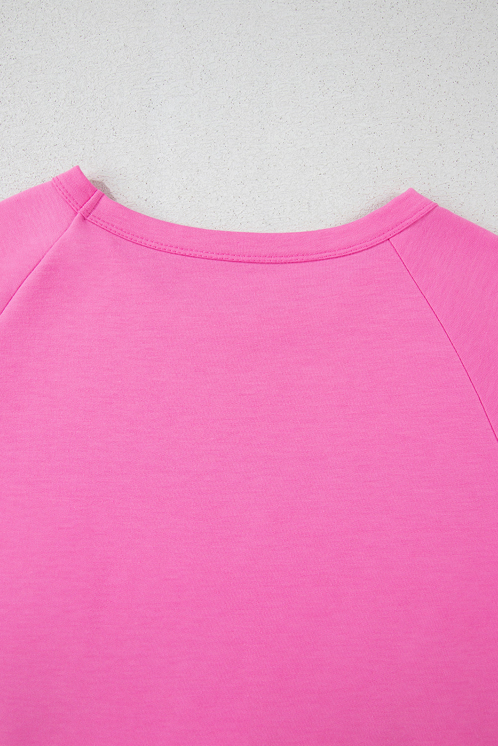 Close-up of the soft pink fabric and crew neck design of a women's casual short sleeve T-shirt.