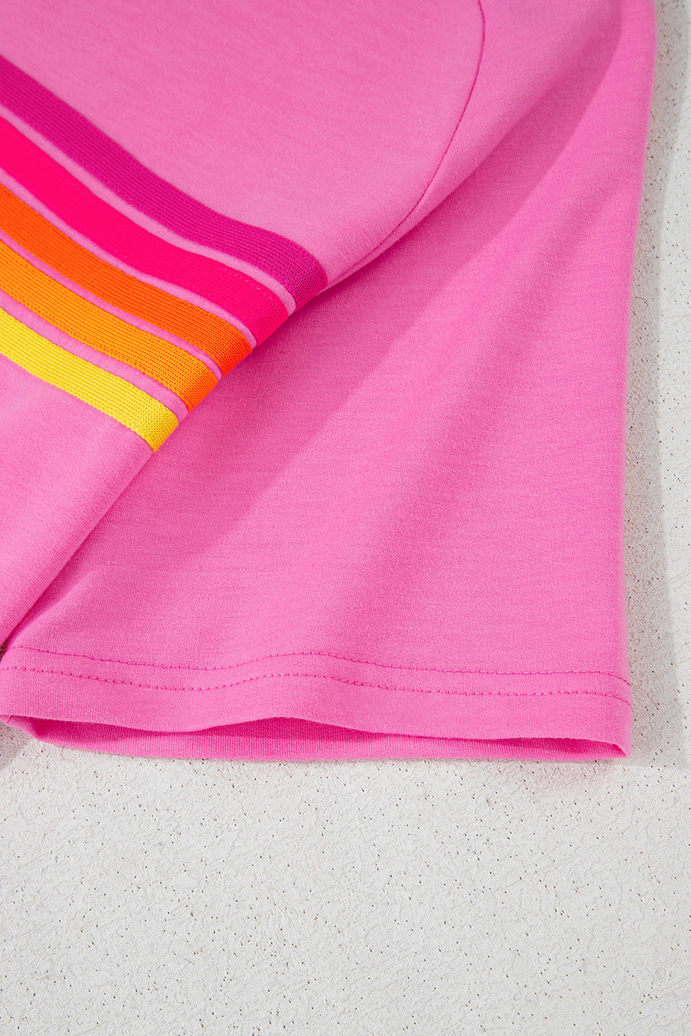 Close-up of the short sleeve and vibrant striped accent on a pink women's casual tee.