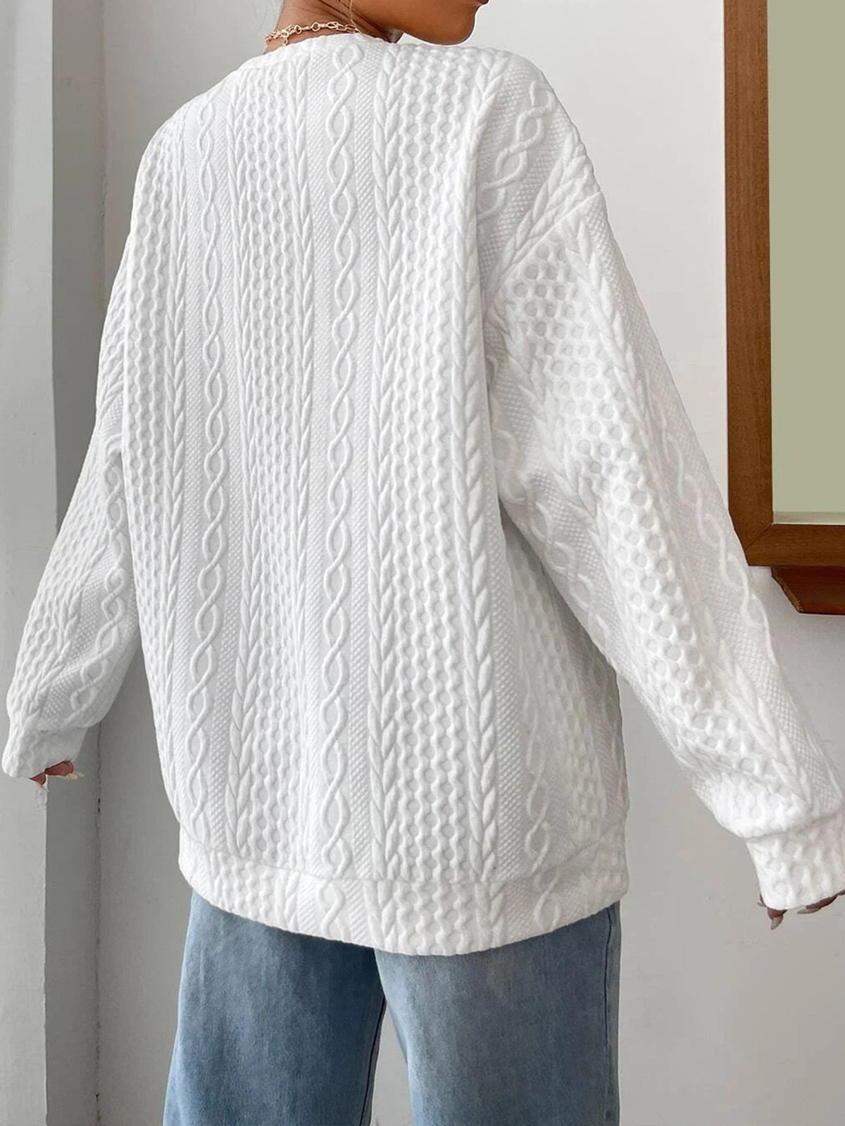 Back view of white cable-knit oversized pullover sweater showing knit texture