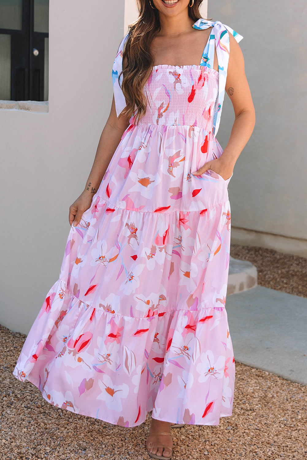 Angled back view of a pink floral maxi dress featuring a sleeveless design and flowing tiered skirt.