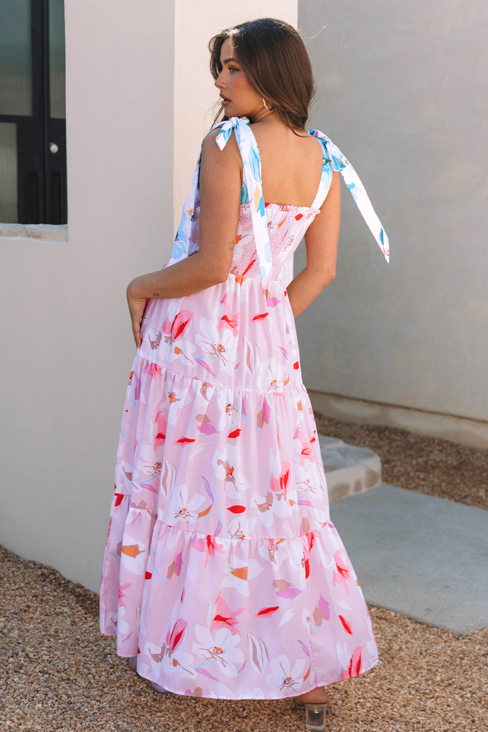 Back view of a pink floral sleeveless maxi dress featuring a flowy tiered silhouette and lightweight fabric.