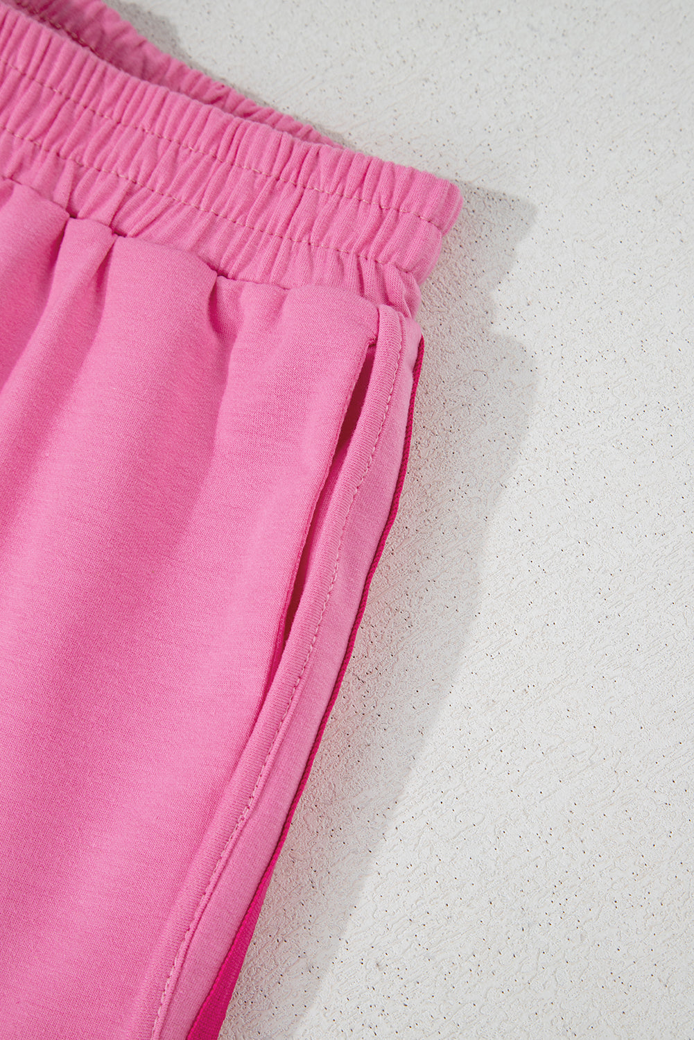 Close-up of the colorful color block side stripe design on pink high-waisted workout shorts.