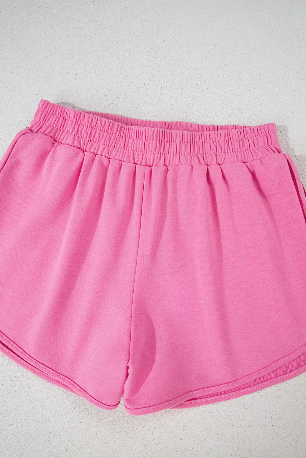 Close-up of the elastic waistband on women's pink high-waisted athletic shorts for a secure, comfortable fit.