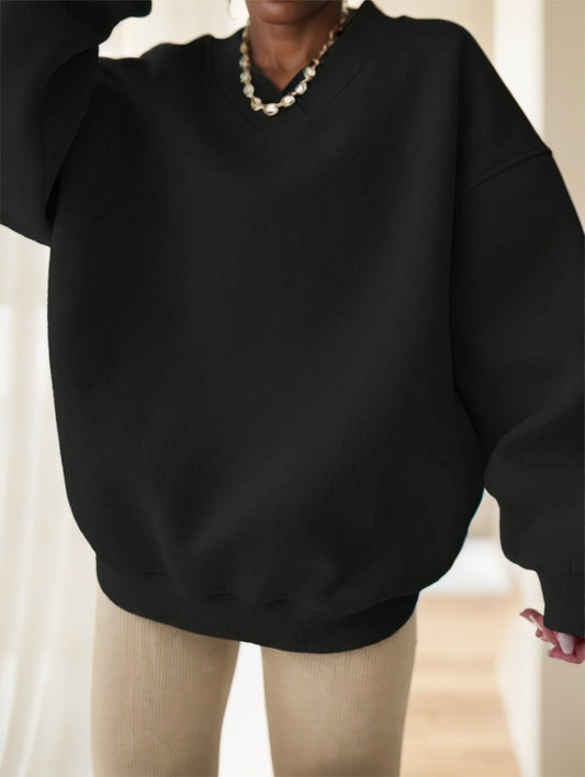 Woman wearing black oversized drop-shoulder sweatshirt, close-up front view